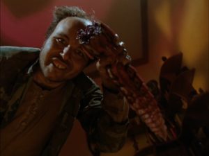 Ricky (Clint Howard) salutes the camera with a creature's broken off appendage in Silent Night, Deadly Night 4