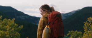 Joy (Hannah Emily Anderson) surveys the land, clad in yellow jacket and red hiking backpack